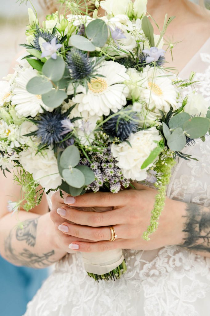 Braut hält weißen Blumenstrauß mit grünen Akzenten