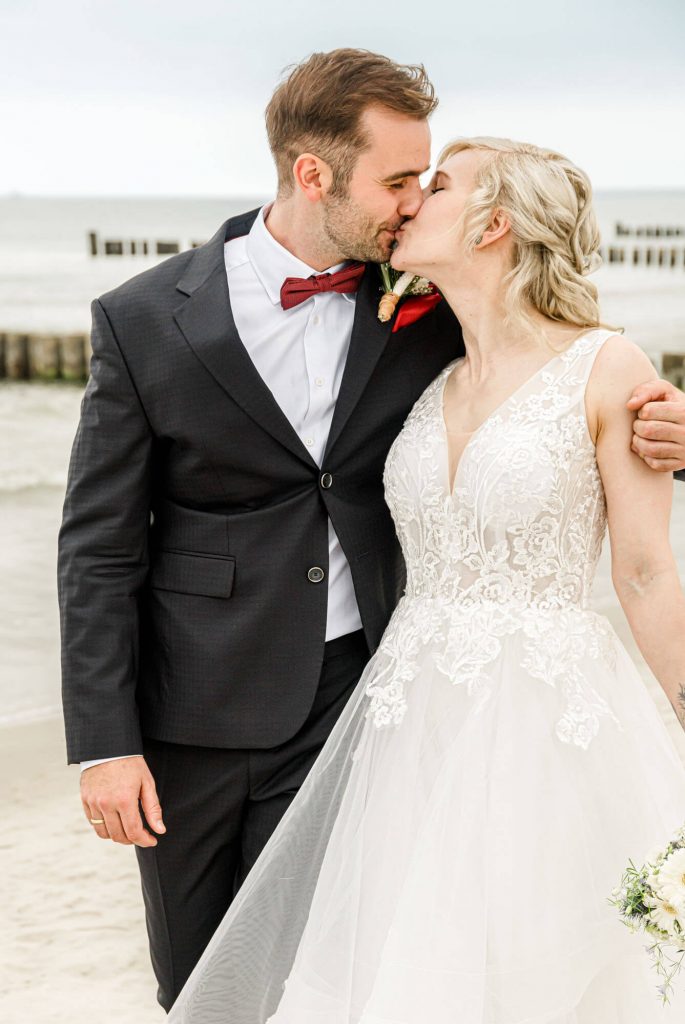 Brautpaar küsst sich am Strand bei Hochzeit