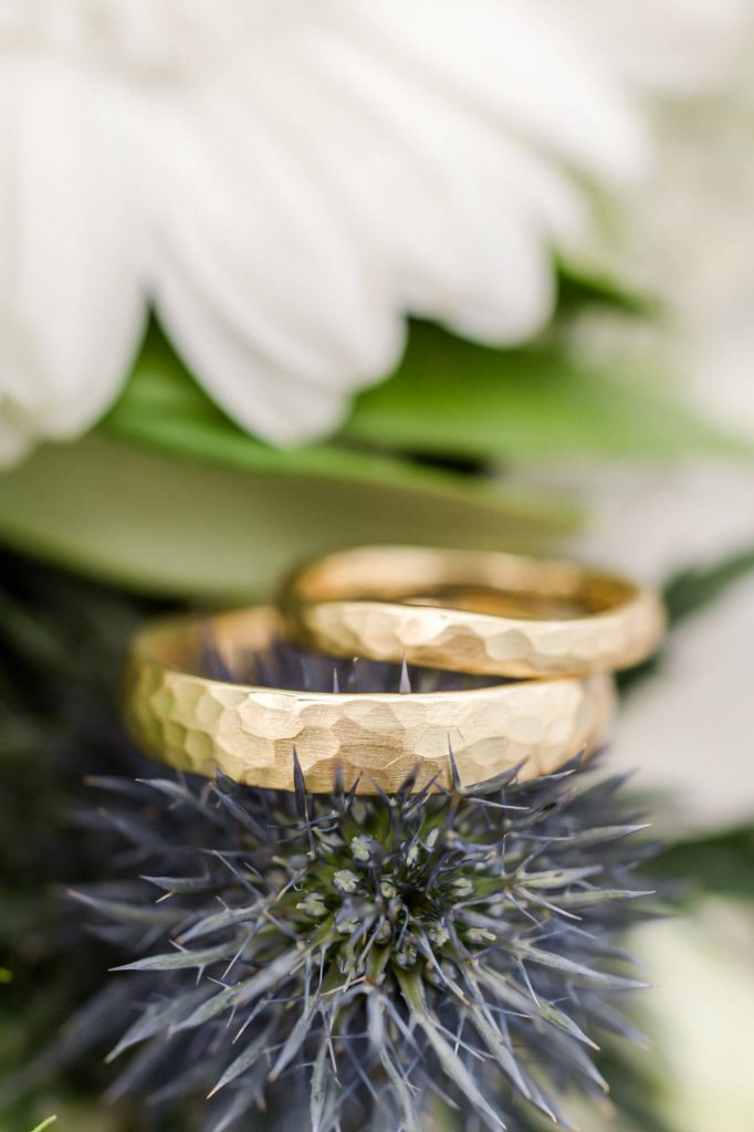 Goldene Eheringe auf Blumenarrangement mit Blüten