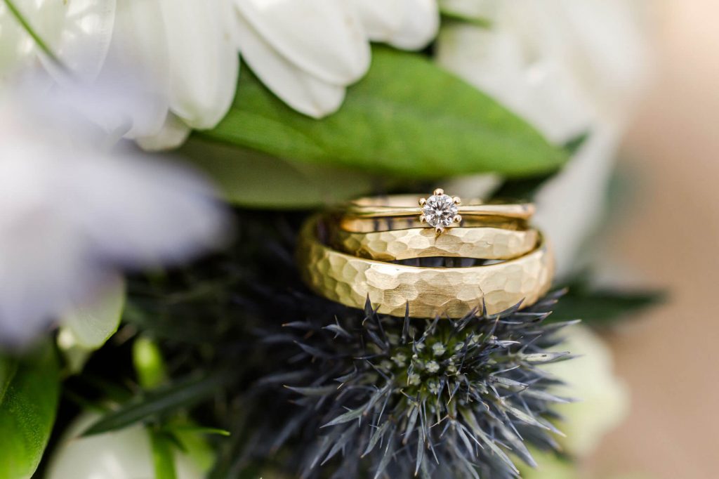 Zwei goldene Eheringe auf Blumendekoration platziert