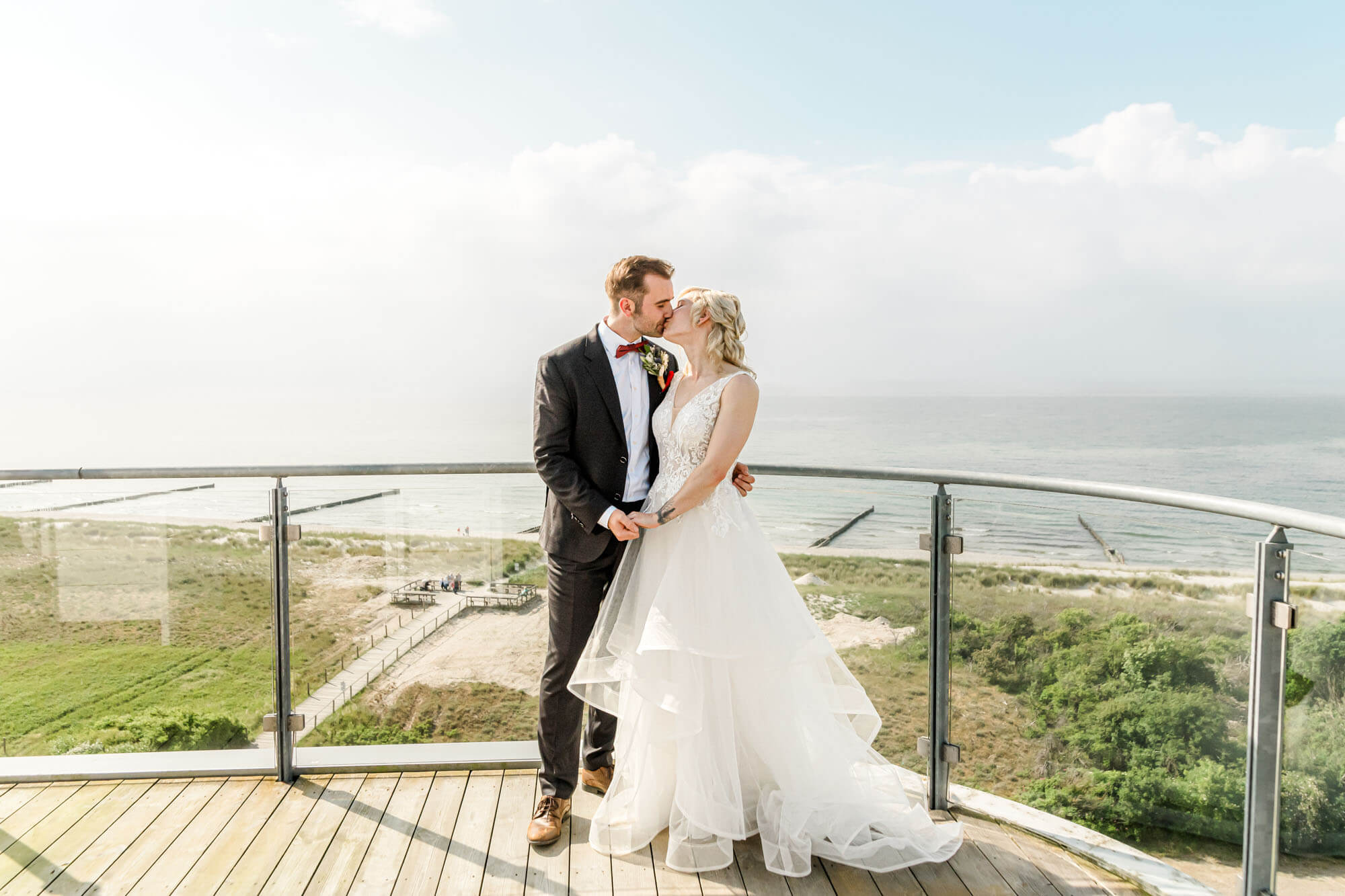 Brautpaar küsst sich auf Balkon mit Meerblick