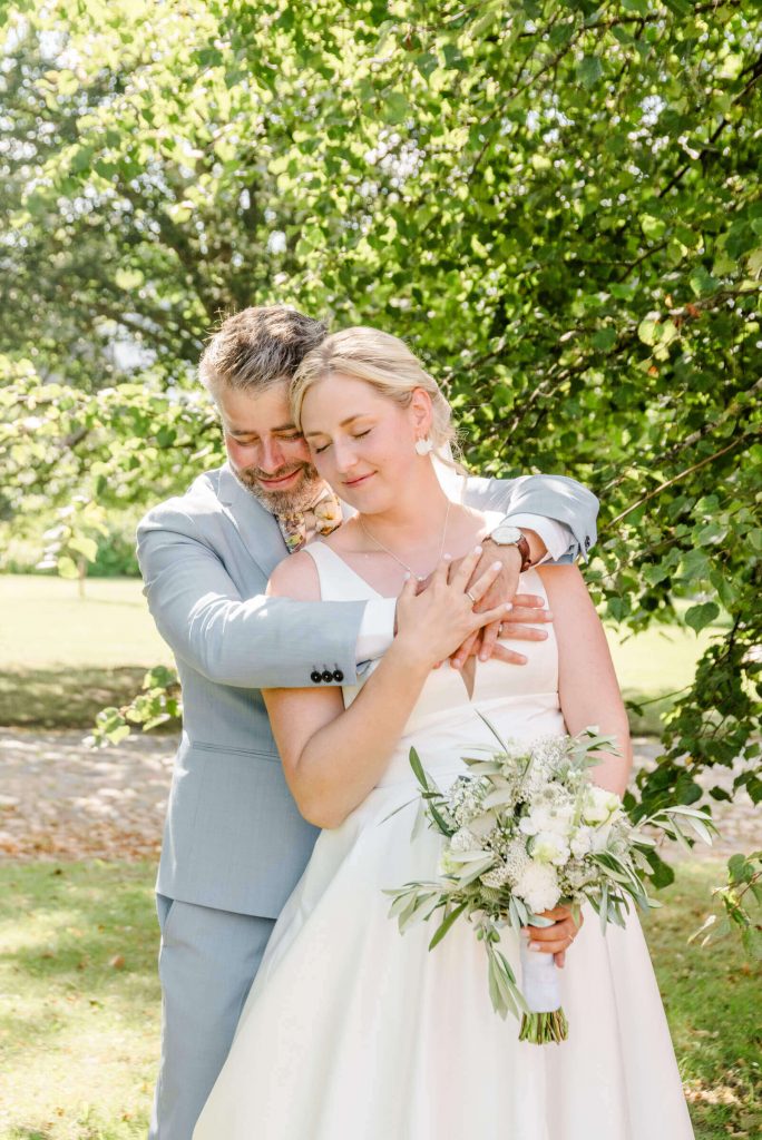 Bräutigam umarmt Braut romantisch im Freien