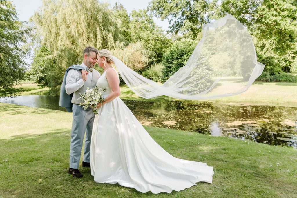 Brautpaar posiert glücklich im sonnigen Garten.