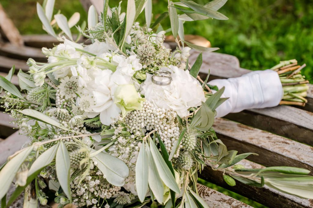 Hochzeitsstrauß aus weißen Blumen auf Bank.