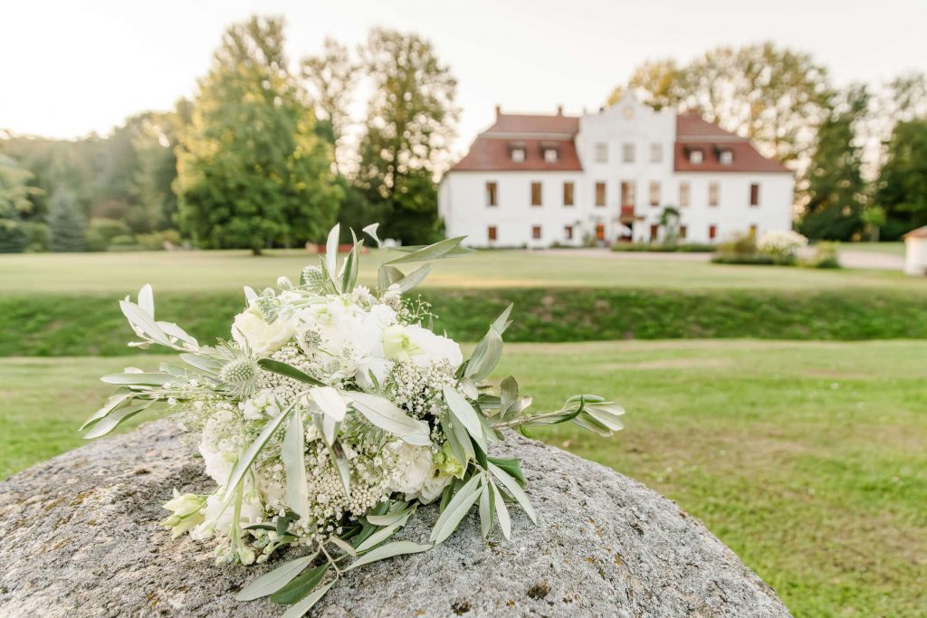 Hochzeitsstrauß vor einem malerischen Landschloss