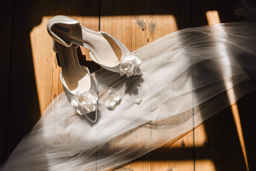 Brautschuhe mit Schleier auf Holzboden drapiert