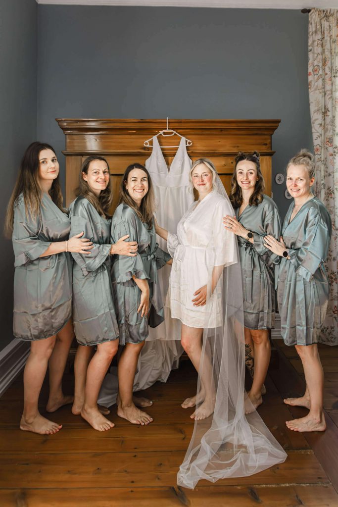 Bräutejungfern und Braut mit Brautkleid im Hintergrund