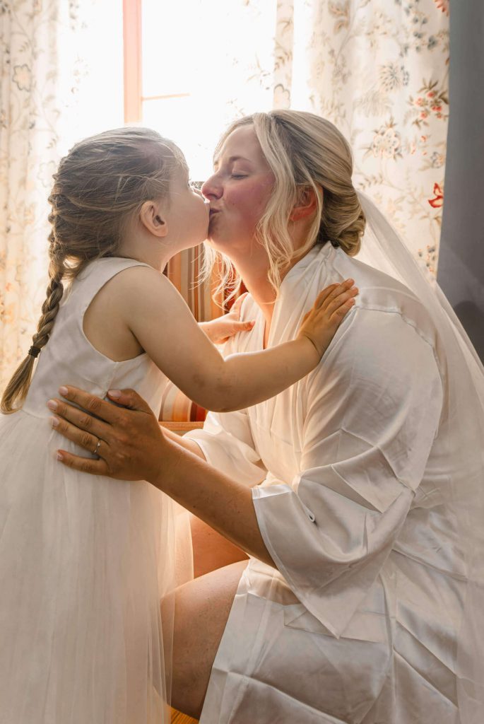 Braut und kleines Mädchen teilen zärtlichen Kuss