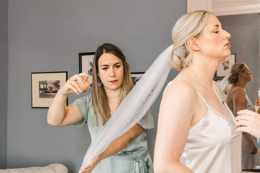 Frau richtet Schleier einer Braut in weiß