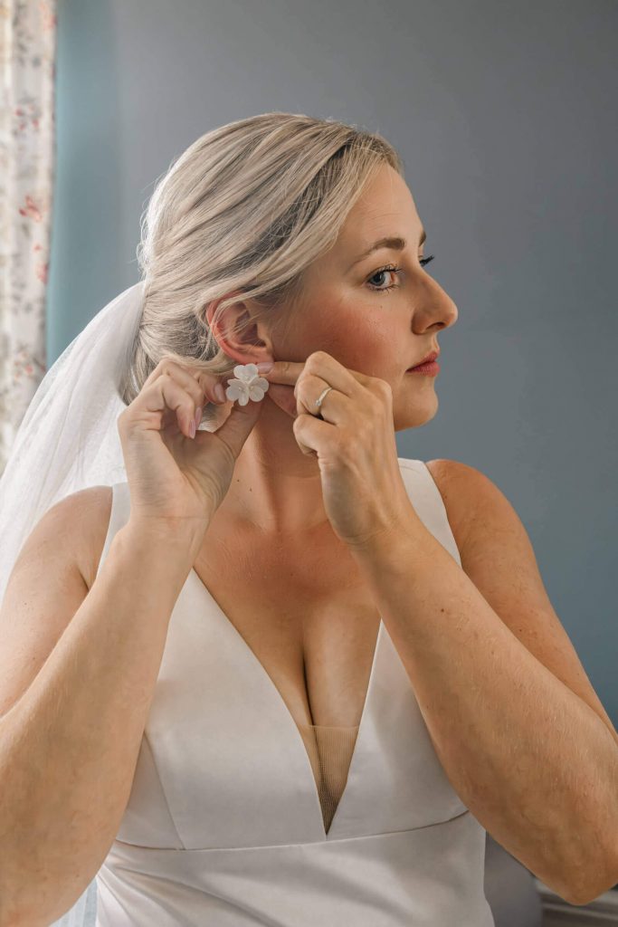 Braut trägt Ohrringe für ihre Hochzeit.