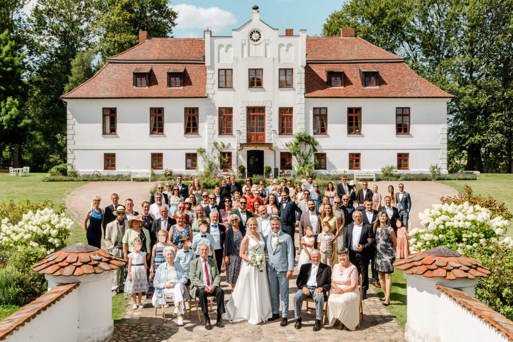 Hochzeitsgesellschaft vor historischem Herrenhaus im Freien