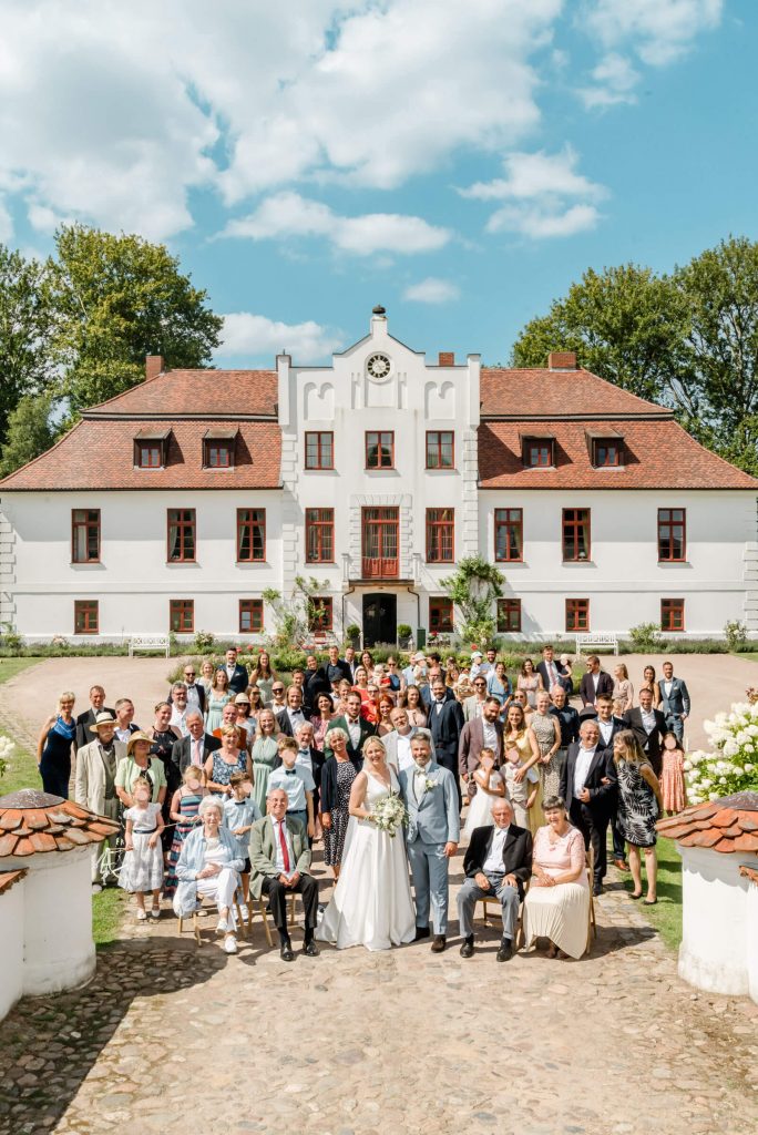 Hochzeitsgesellschaft vor historischer weißer Villa versammelt