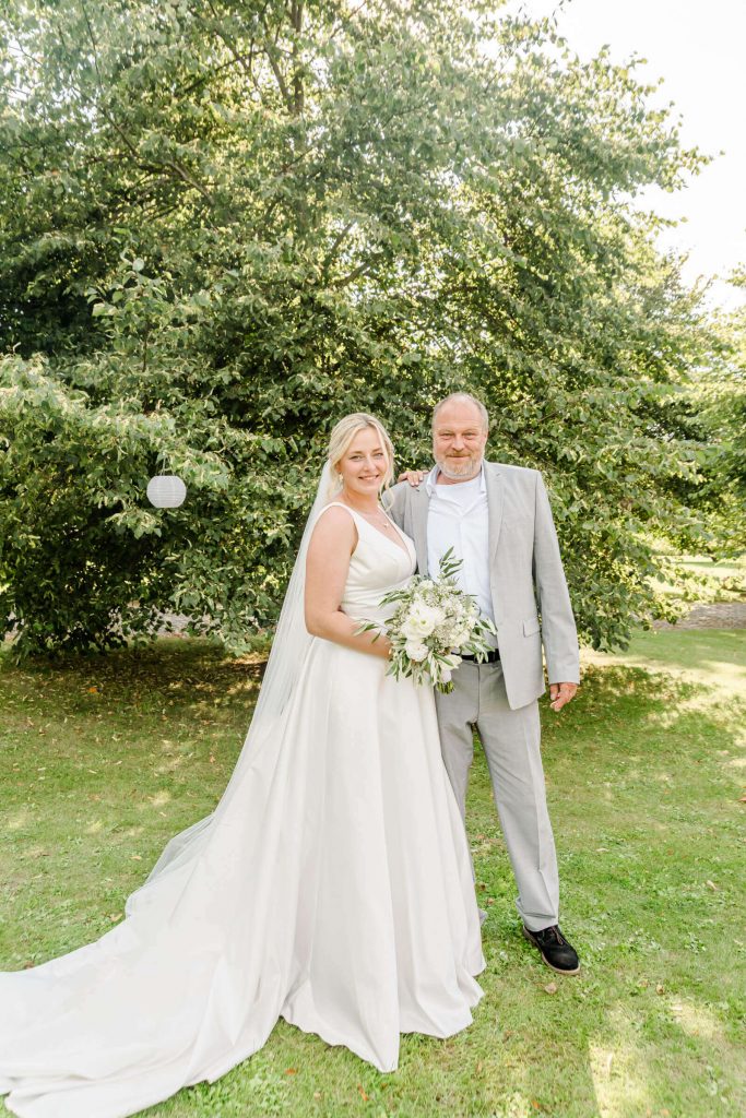 Hochzeitspaar steht lächelnd im grünen Garten