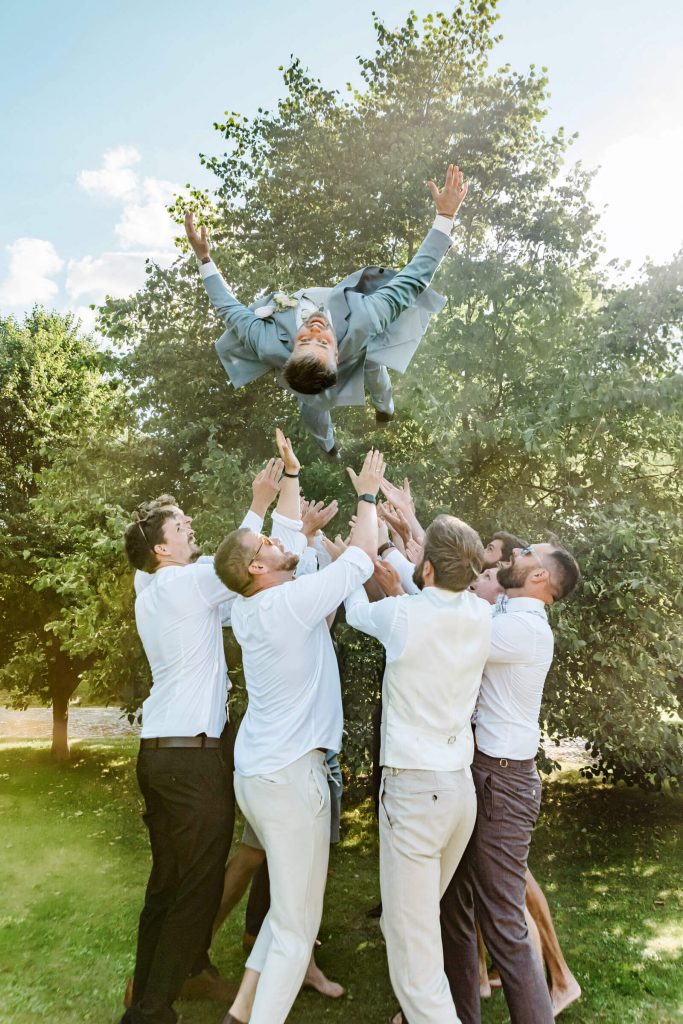 Männer werfen lachenden Freund in die Luft.