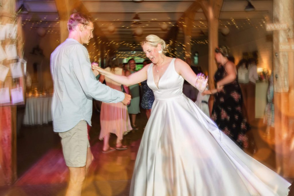 Braut tanzt mit Gast bei Hochzeitsfeier
