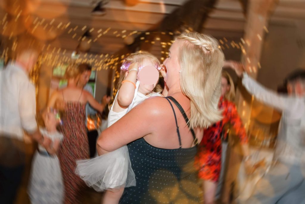 Frau tanzt mit Kind bei Feierlichkeiten drinnen