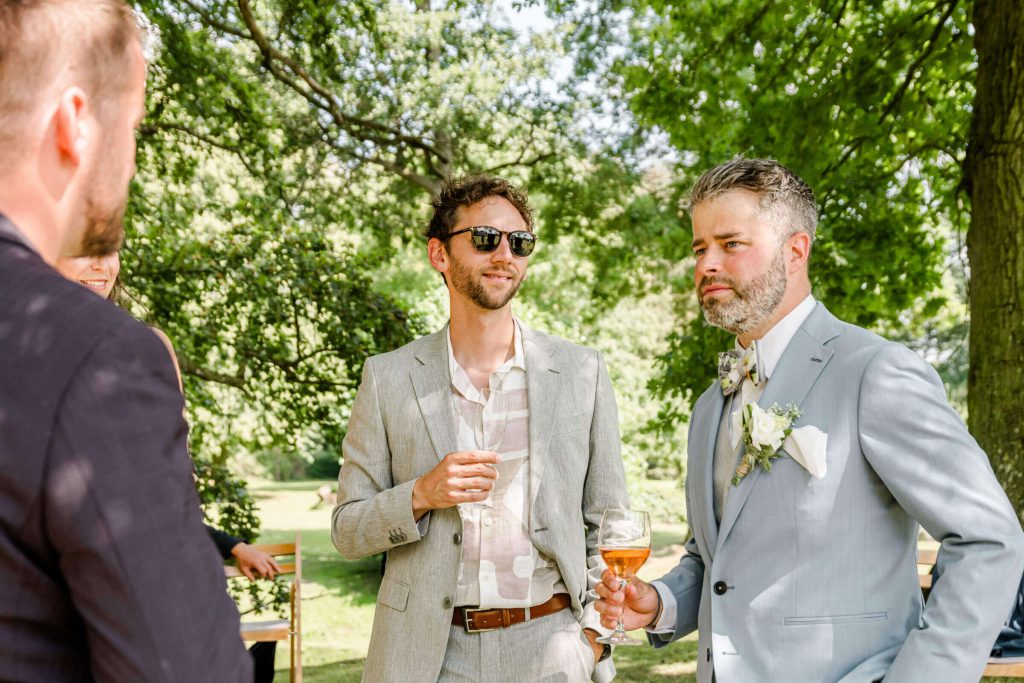 Männer bei einer Hochzeit im Freien sprechen.