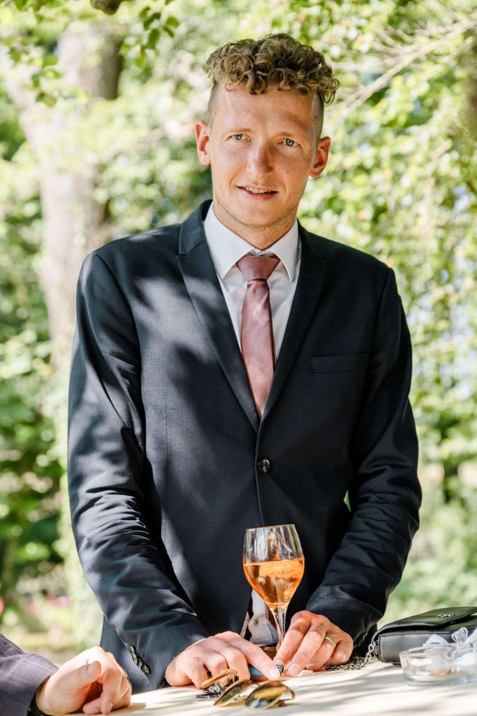 Mann im Anzug mit Getränk im Freien