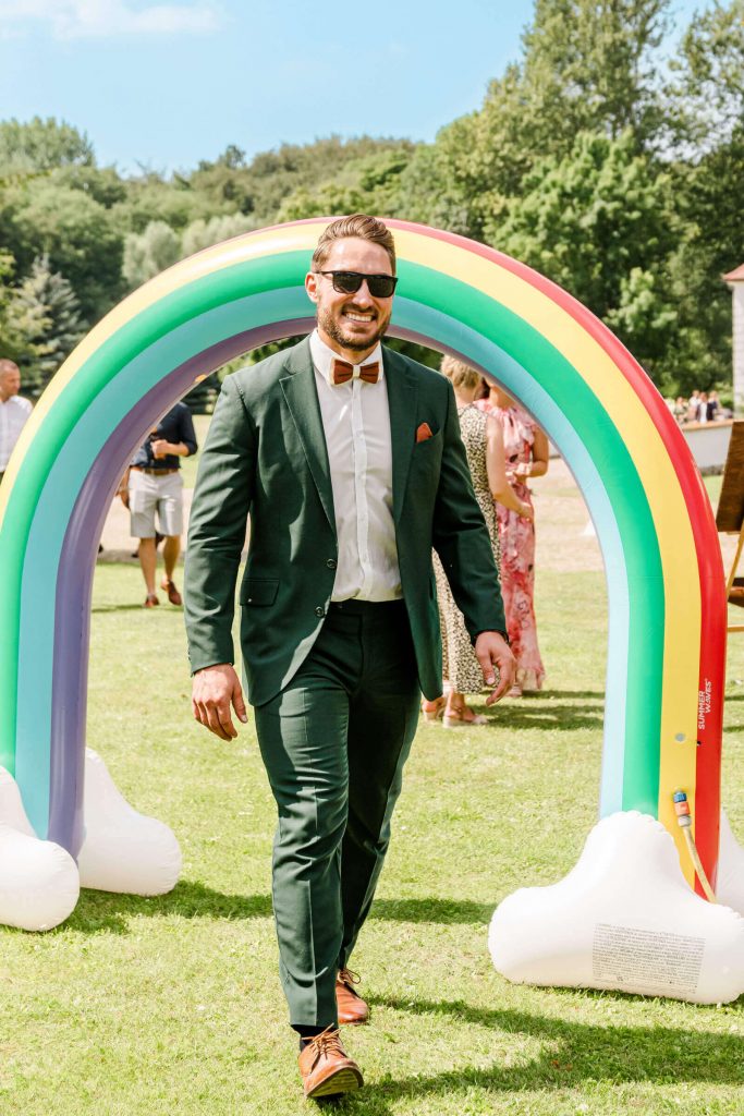 Mann im Anzug unter Regenbogenbogen draußen