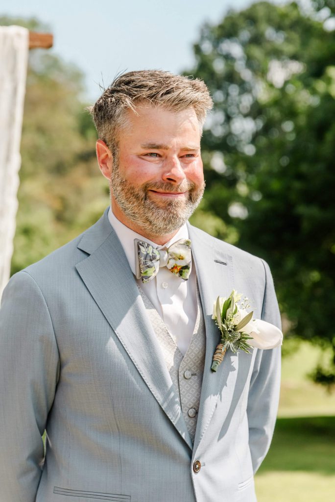 Bräutigam in grauem Anzug mit Blumenanstecker