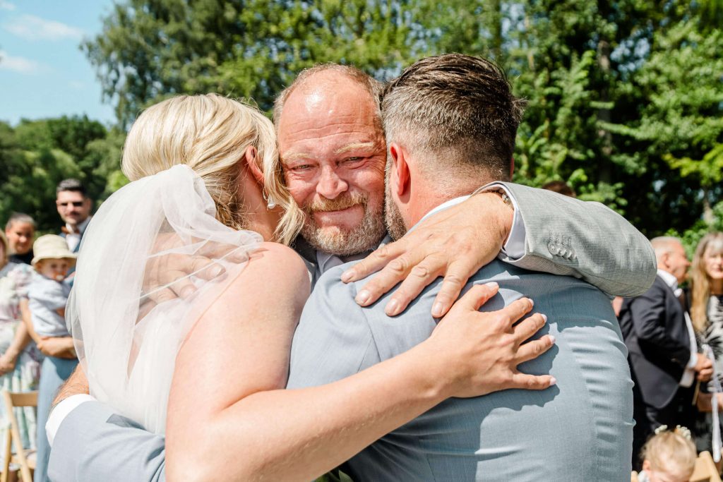 Personen umarmen sich bei einer Hochzeit im Freien