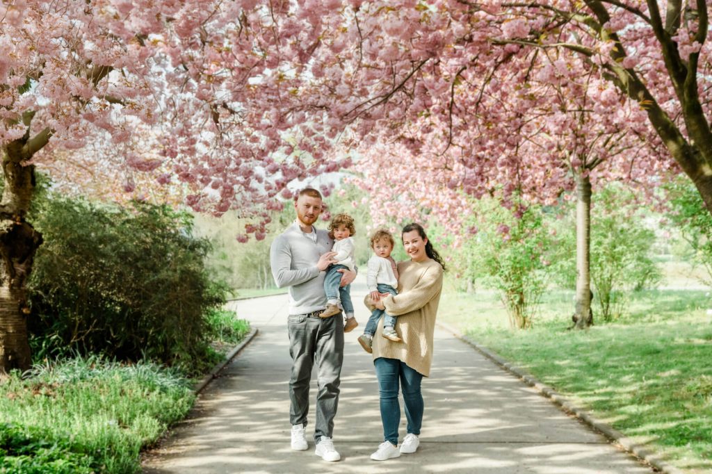 Familie spaziert unter blühenden Kirschbäumen im Park