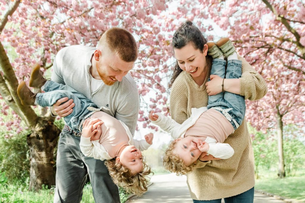 Glückliche Familie spielt im Park unter Kirschblüten