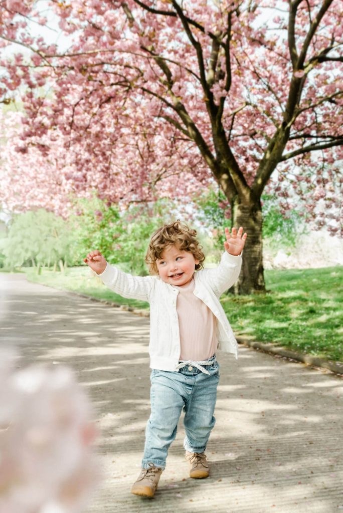 Kleinkind spielt fröhlich unter blühenden Kirschbäumen