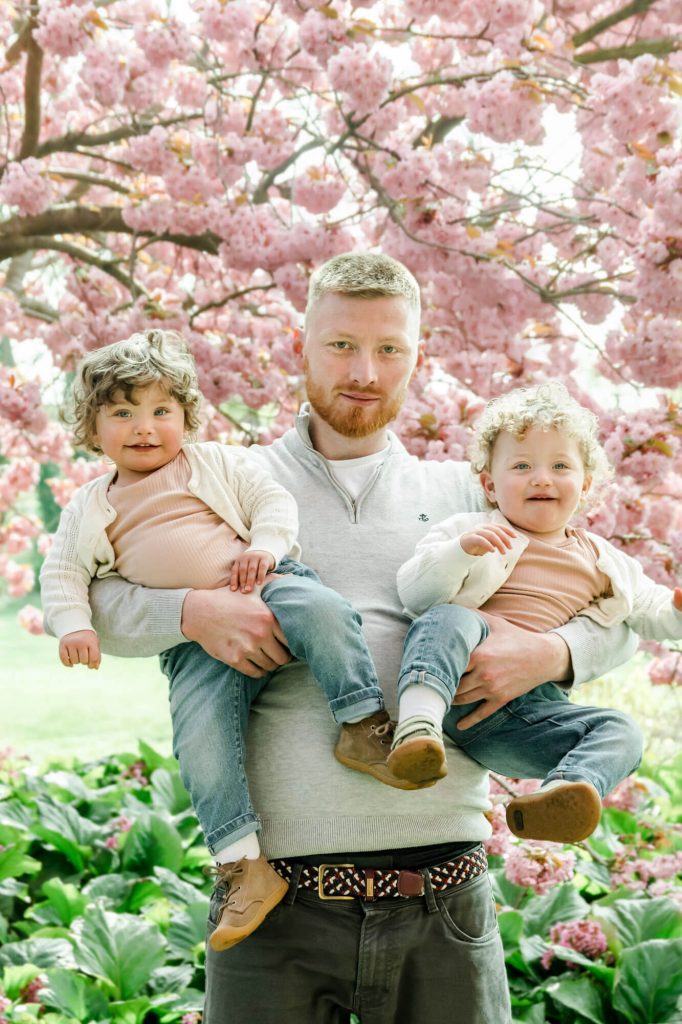 Vater mit Zwillingen vor blühendem Kirschbaum