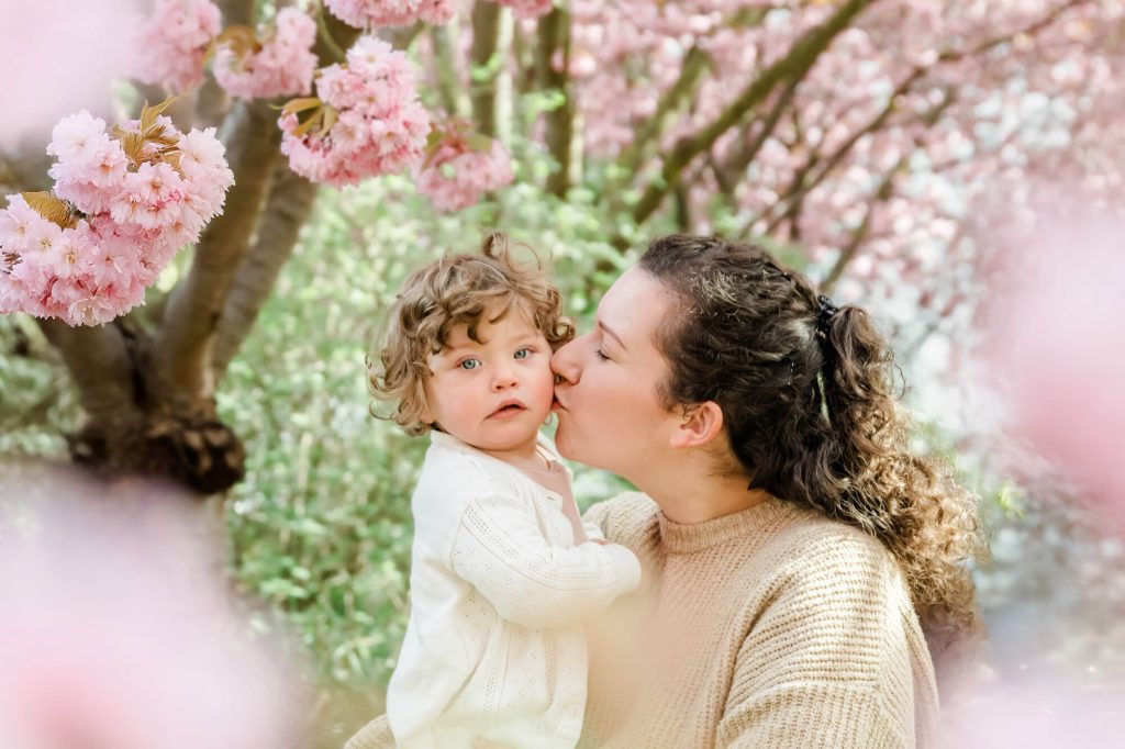 Mutter und Kind unter blühenden Kirschbäumen.