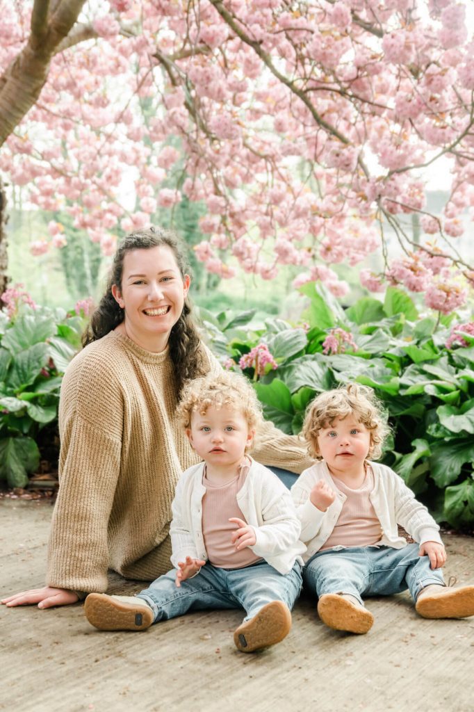 Mutter mit Zwillingen unter Kirschblütenbaum sitzend