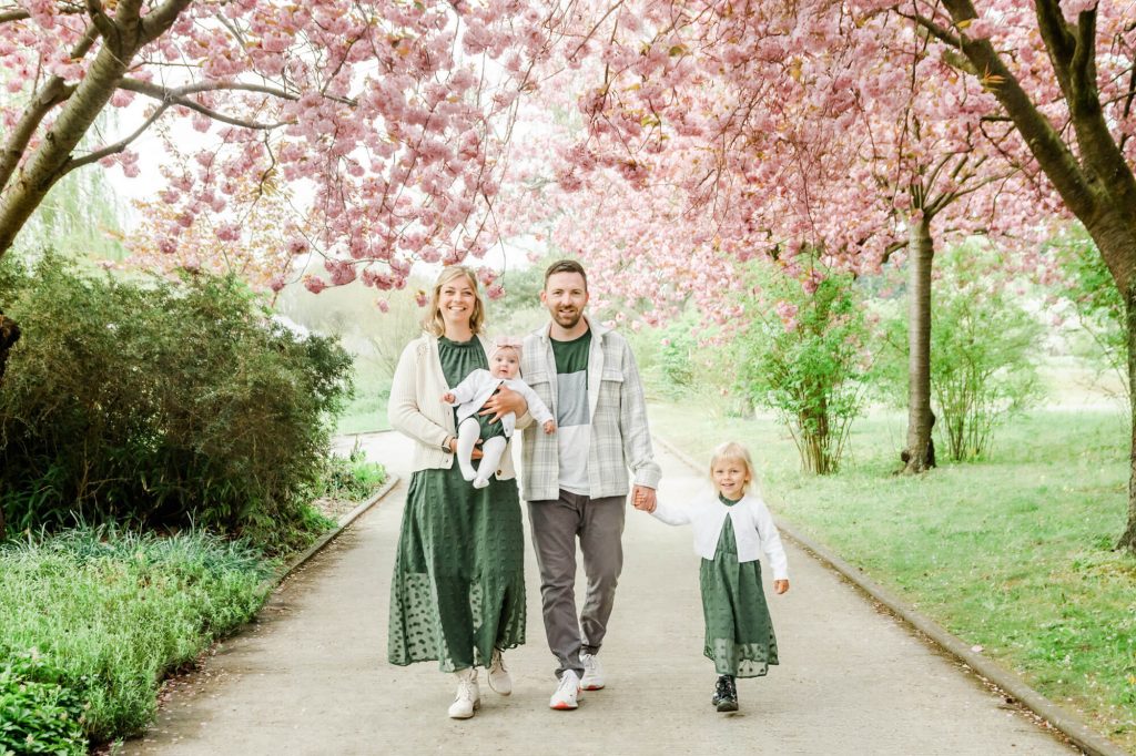 Familie spaziert unter blühenden Kirschbäumen im Park