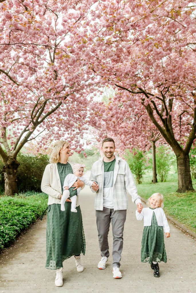 Familie spaziert unter blühenden Kirschbäumen im Frühling
