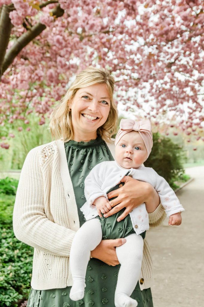 Frau mit Baby vor blühendem Kirschbaum