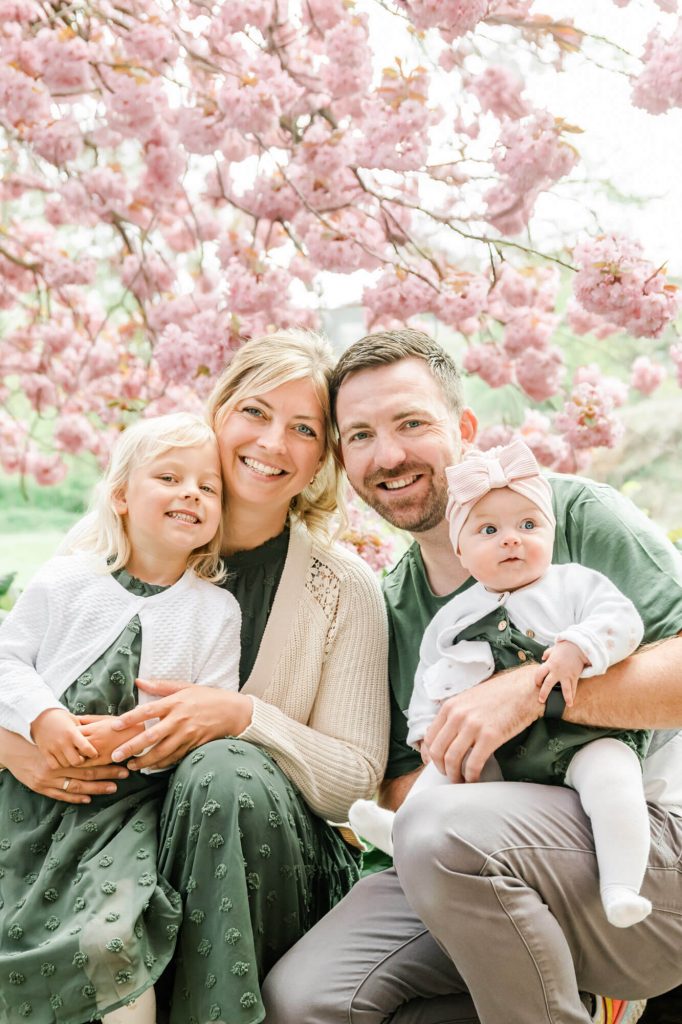Familie lächelt unter blühenden Kirschblütenbäumen