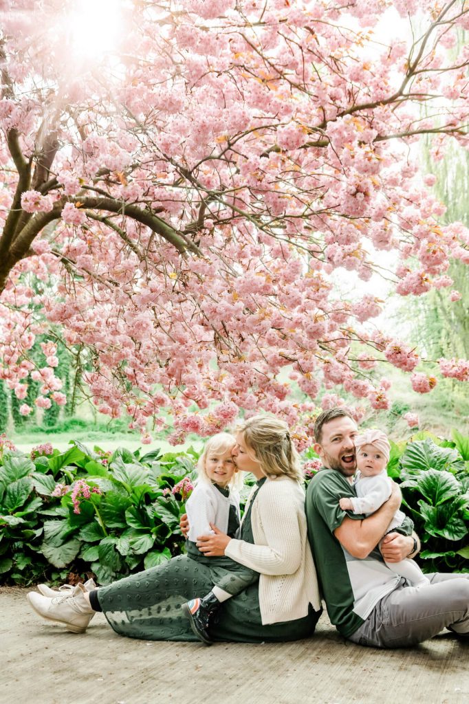 Familie sitzt unter blühendem Kirschbaum im Park