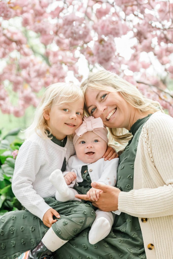 Glückliche Familie unter rosa Kirschblütenbäumen