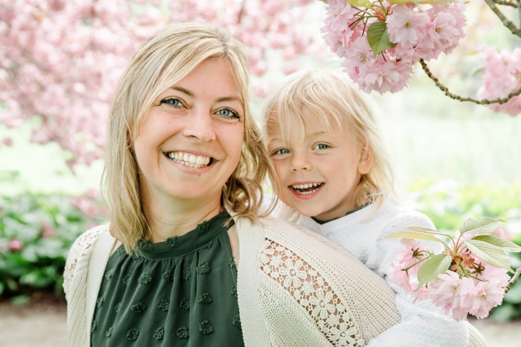 Lächelnde Mutter mit Kind unter Kirschblüten