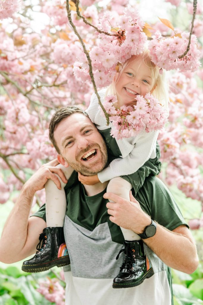 Mann und Kind unter blühendem Kirschbaum lachen
