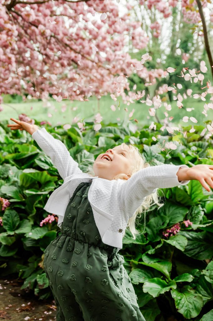 Kind spielt fröhlich unter blühendem Baum.