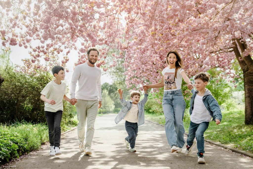 Familie spaziert fröhlich unter blühenden Kirschbäumen