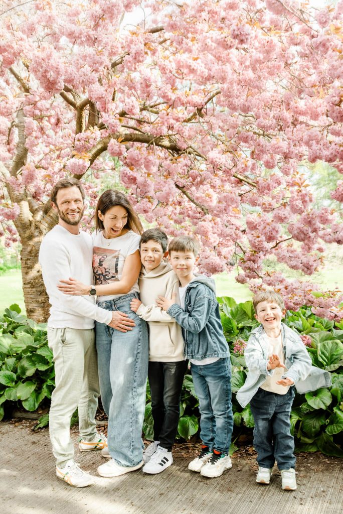 Familie posiert unter blühendem Kirschbaum im Park