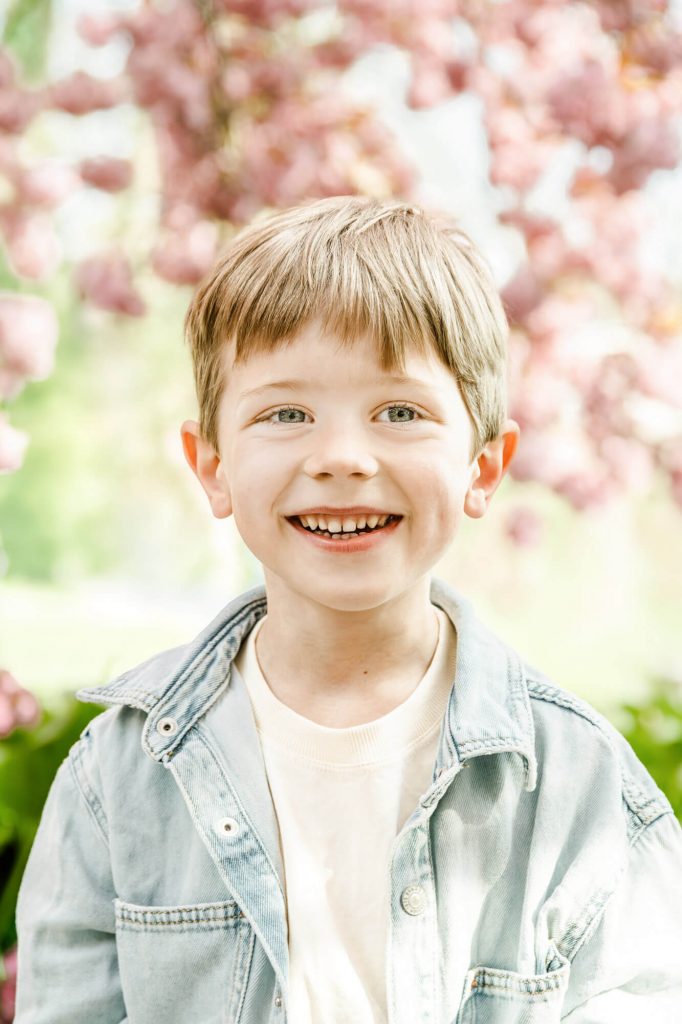 Lächelnder Junge vor blühendem Kirschbaum im Frühling