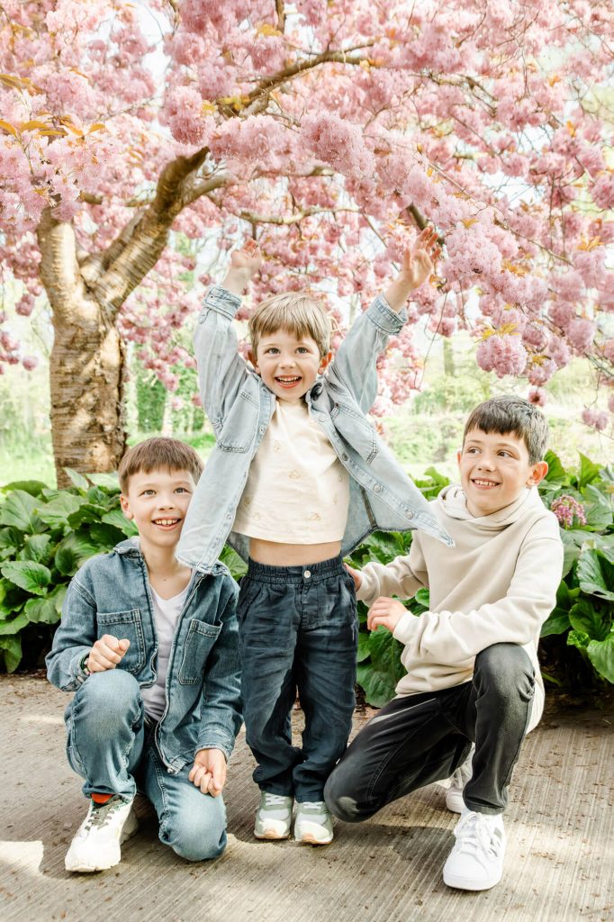 Drei Kinder unter blühendem Kirschbaum im Frühling