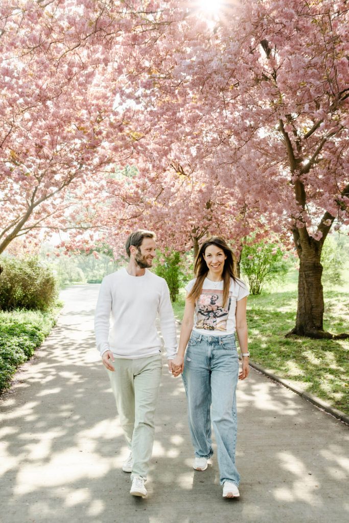 Paar spaziert unter blühenden Kirschbäumen im Frühling