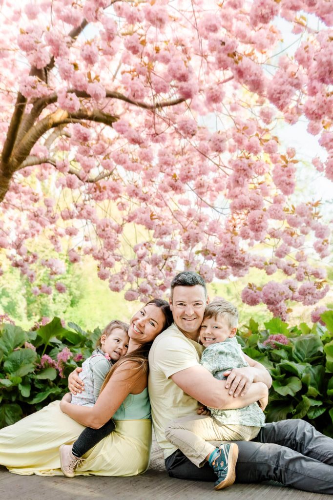 Familie sitzt unter einem blühenden Kirschbaum