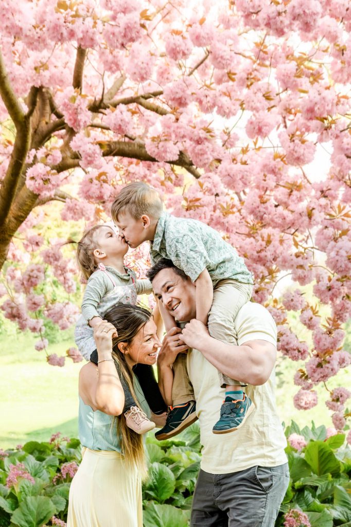 Familie unter blühendem Kirschbaum genießt den Frühling