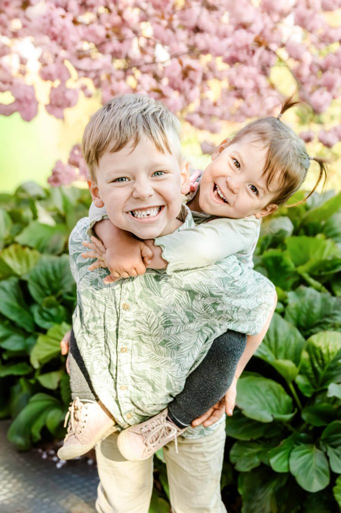 Zwei lachende Kinder unter blühendem Baum im Frühling