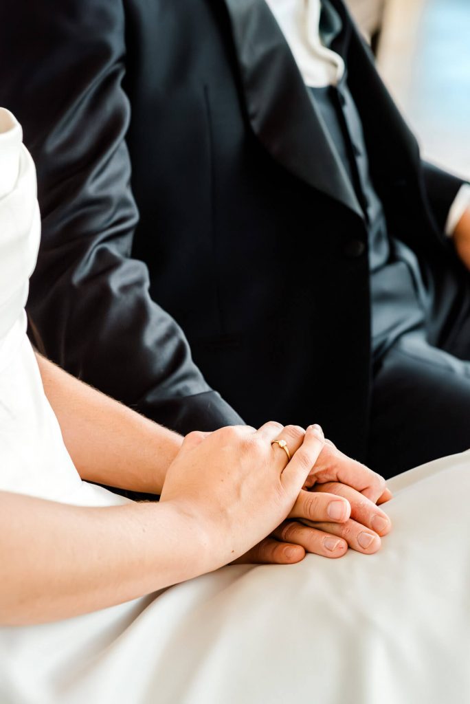 Hände eines Hochzeitspaares mit Trauringen halten