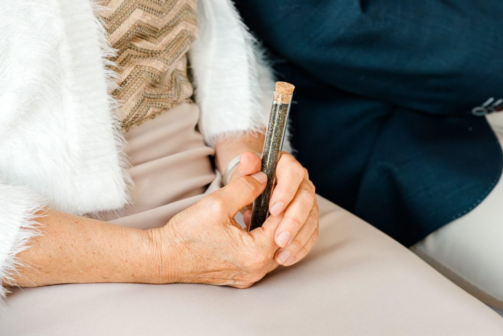 Ältere Person hält kleine Glasflasche in Händen